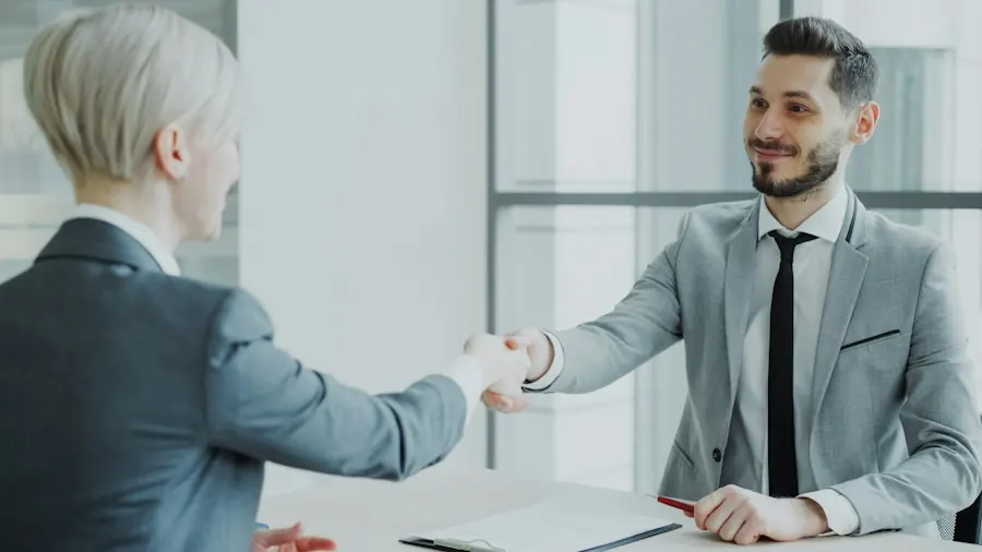 Two people shaking hands in an office after a meeting