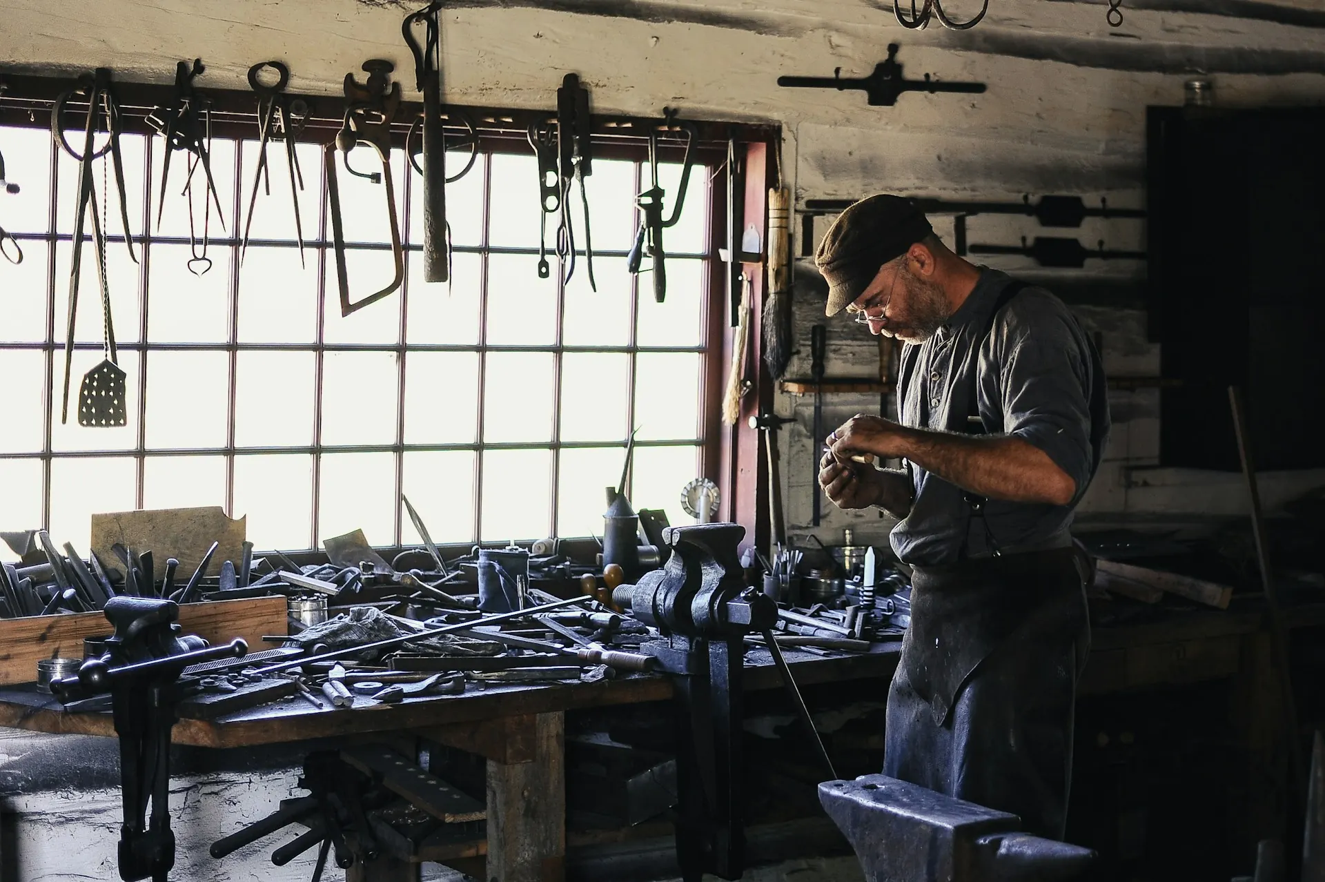 Owner at work in a small tool and woodworking shop lit by tall windows