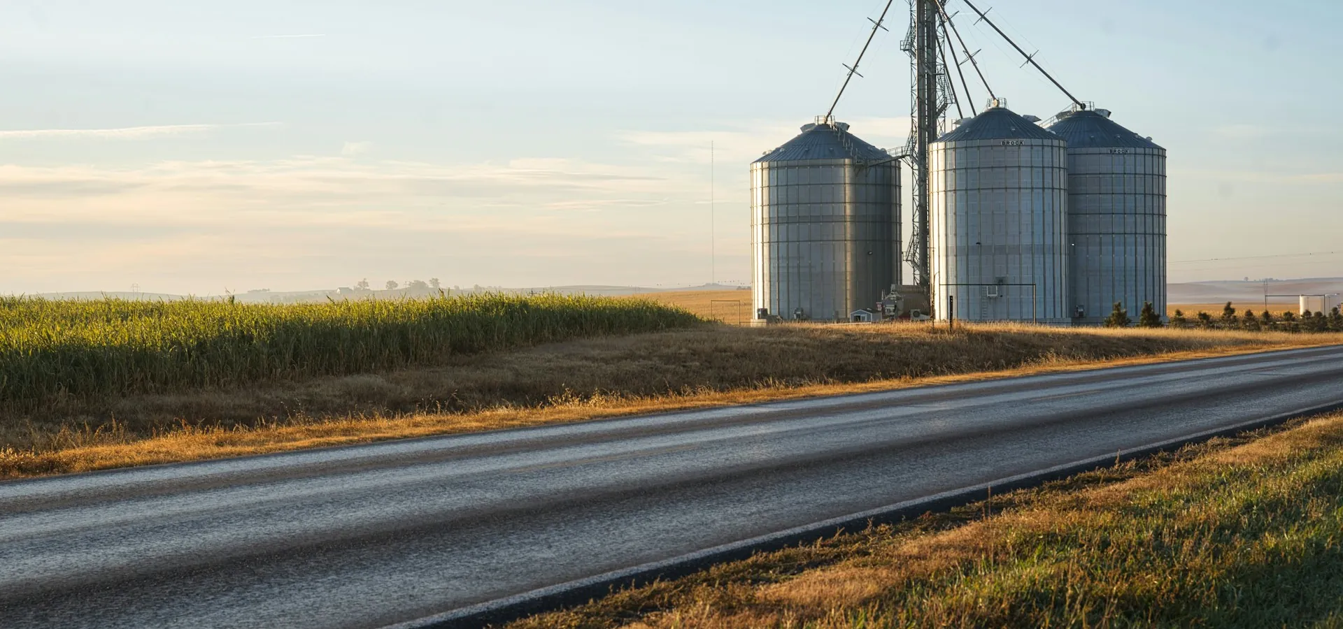 Grain silos beside a two-lane country highway under a wide sky