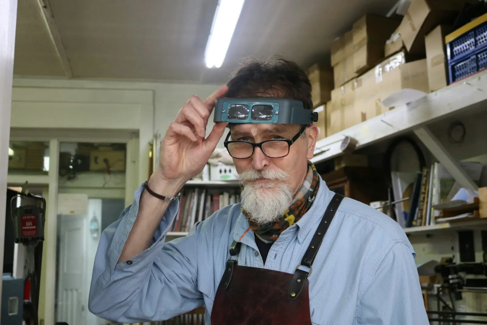 Shop owner adjusting magnifying glasses at his workbench
