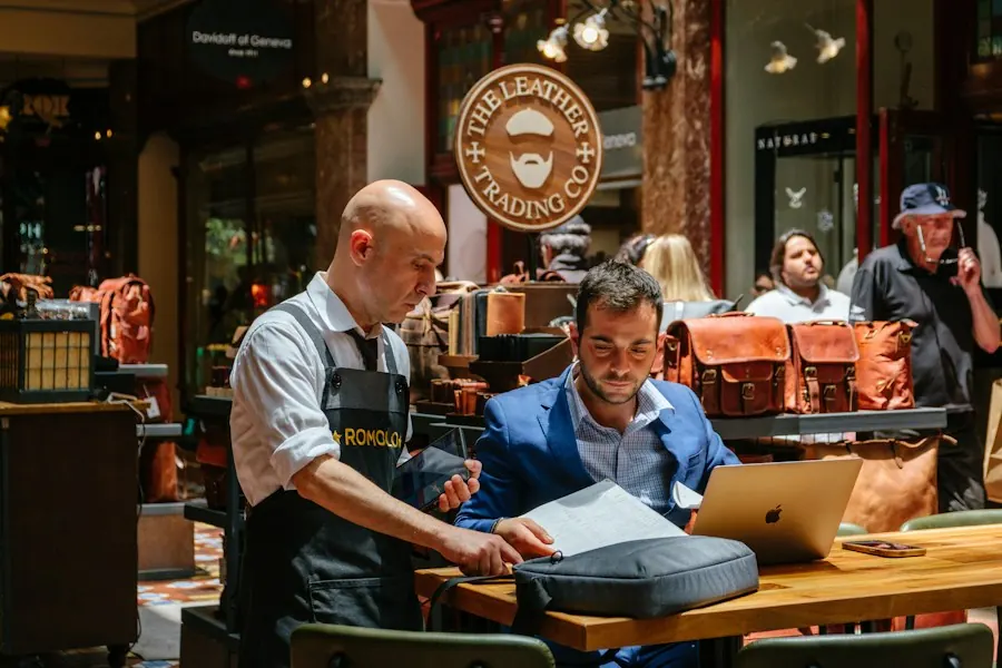 Two men reviewing papers and a laptop in a small store