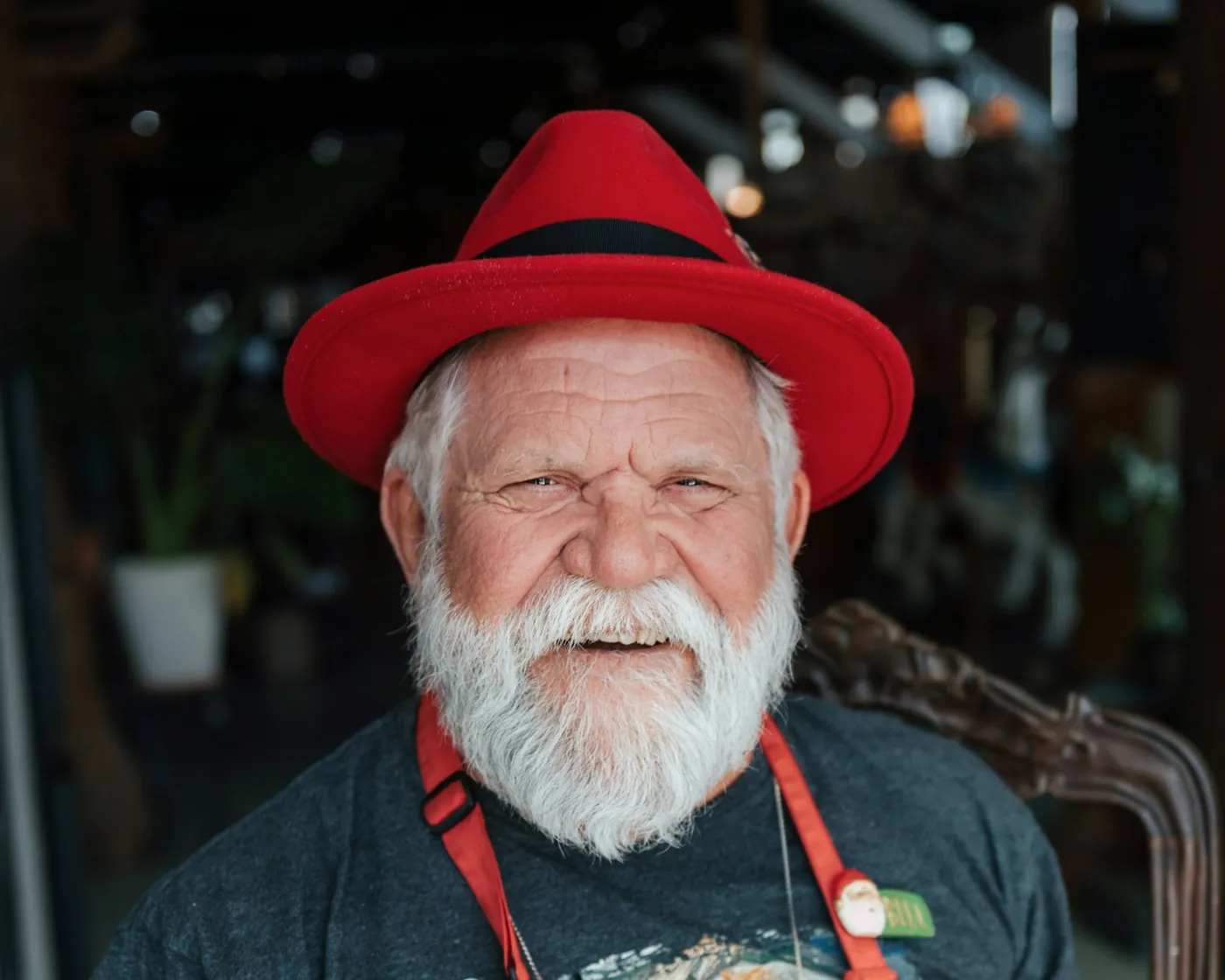 Longtime business owner with a white beard, red hat and work apron inside his shop